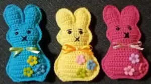 Roztomilé háčkované zvířátko zajíček v různých barvách s ozdobnými květinami a stuhami.