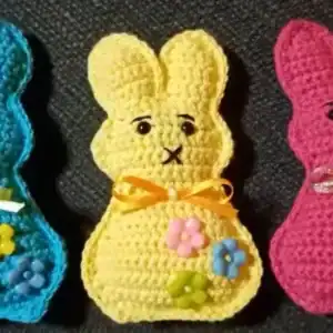 Roztomilé háčkované zvířátko zajíček v různých barvách s ozdobnými květinami a stuhami.